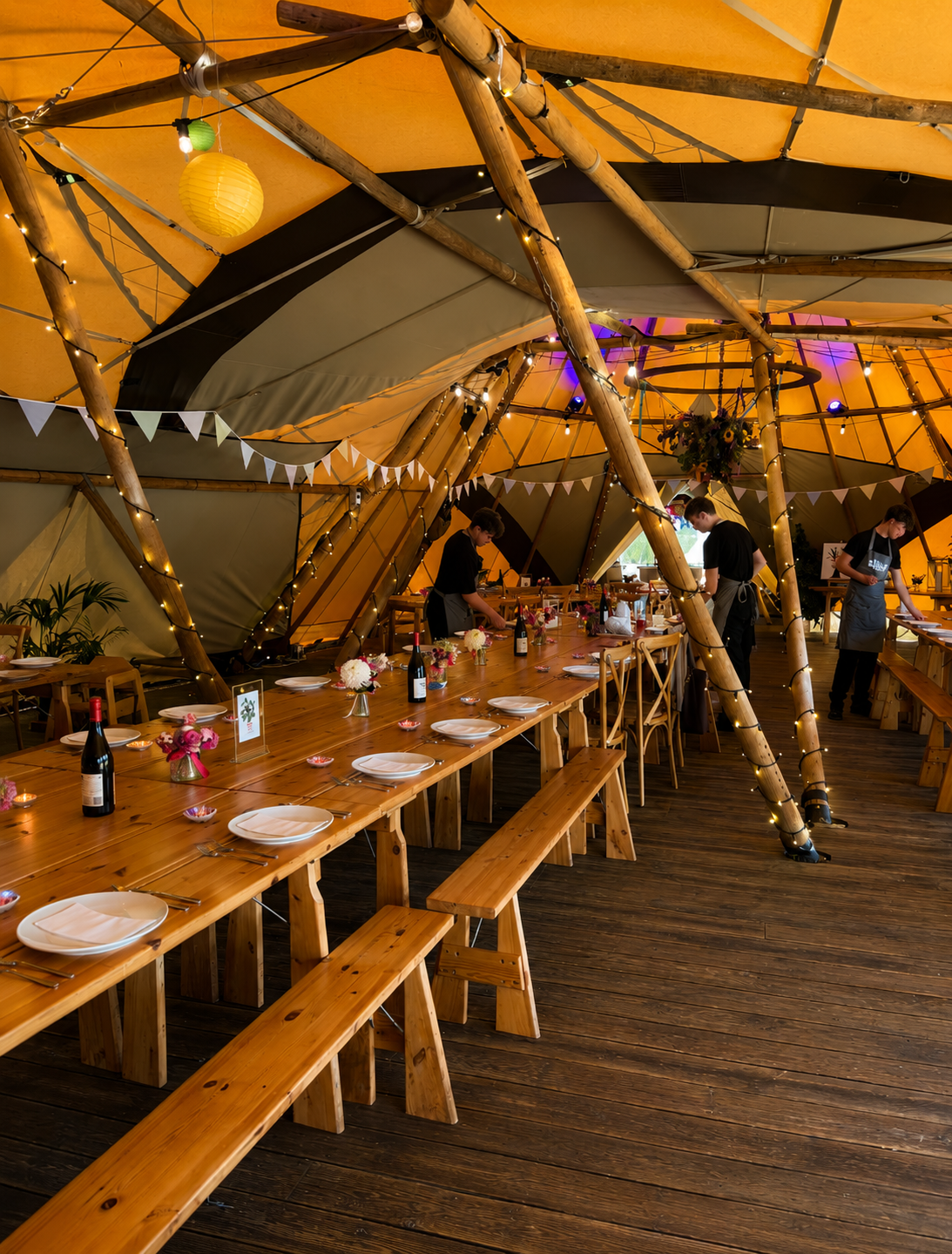 Tilia Bespoke Catering – tipi interior set for a wedding feast with warm golden light and fairy lights
